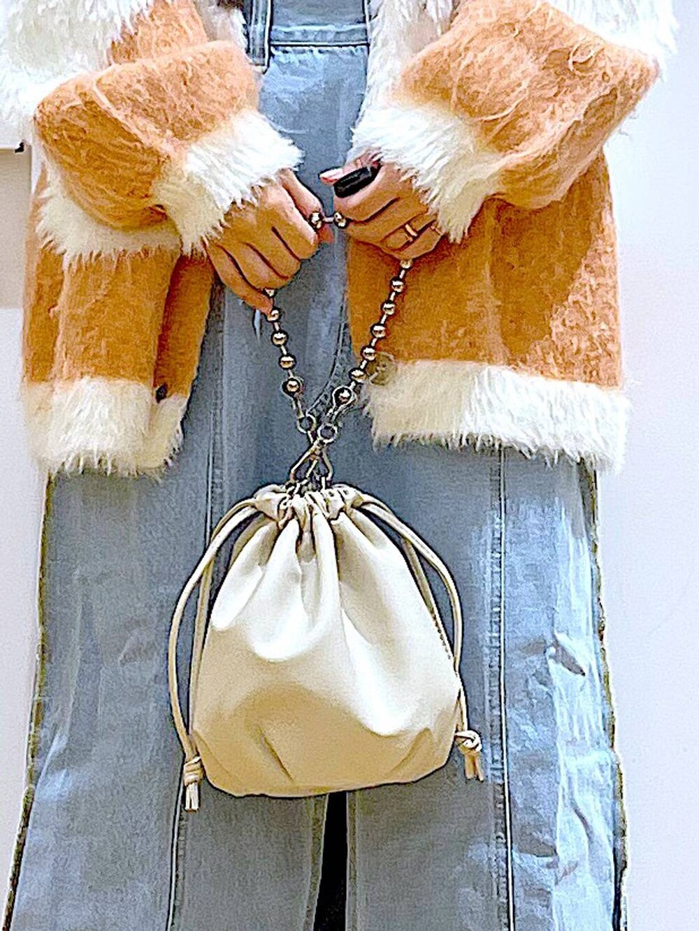 ベージュ系のショルダーバッグ、ブルー系のデニムスカート、ブラック系のブーツを着用したレディースの冬コーディネートの9枚目の写真