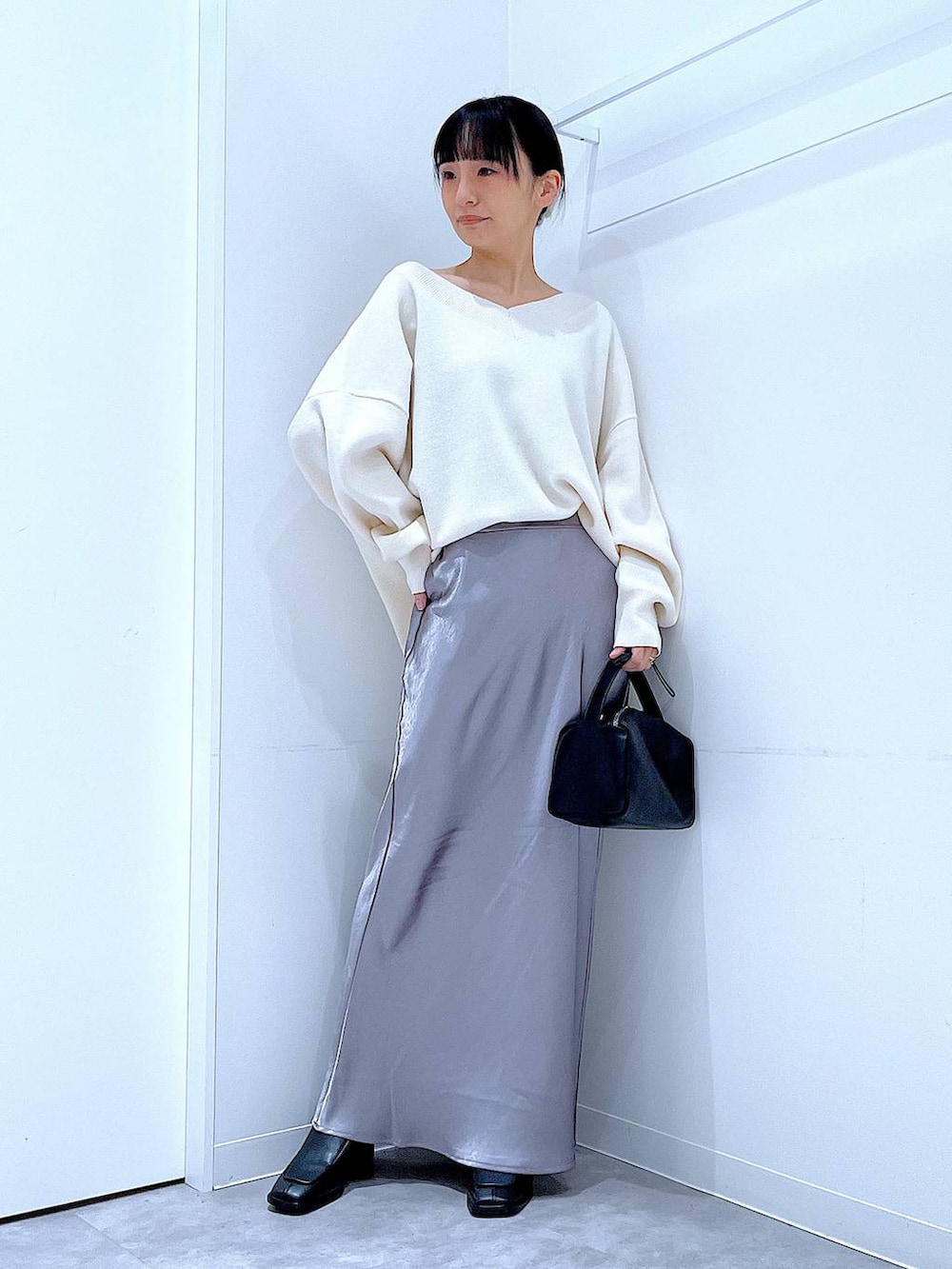 ベージュ系のニット/セーター、ブラック系のブーツ、ブラック系のショルダーバッグを着用したレディースの冬コーディネートの2枚目の写真