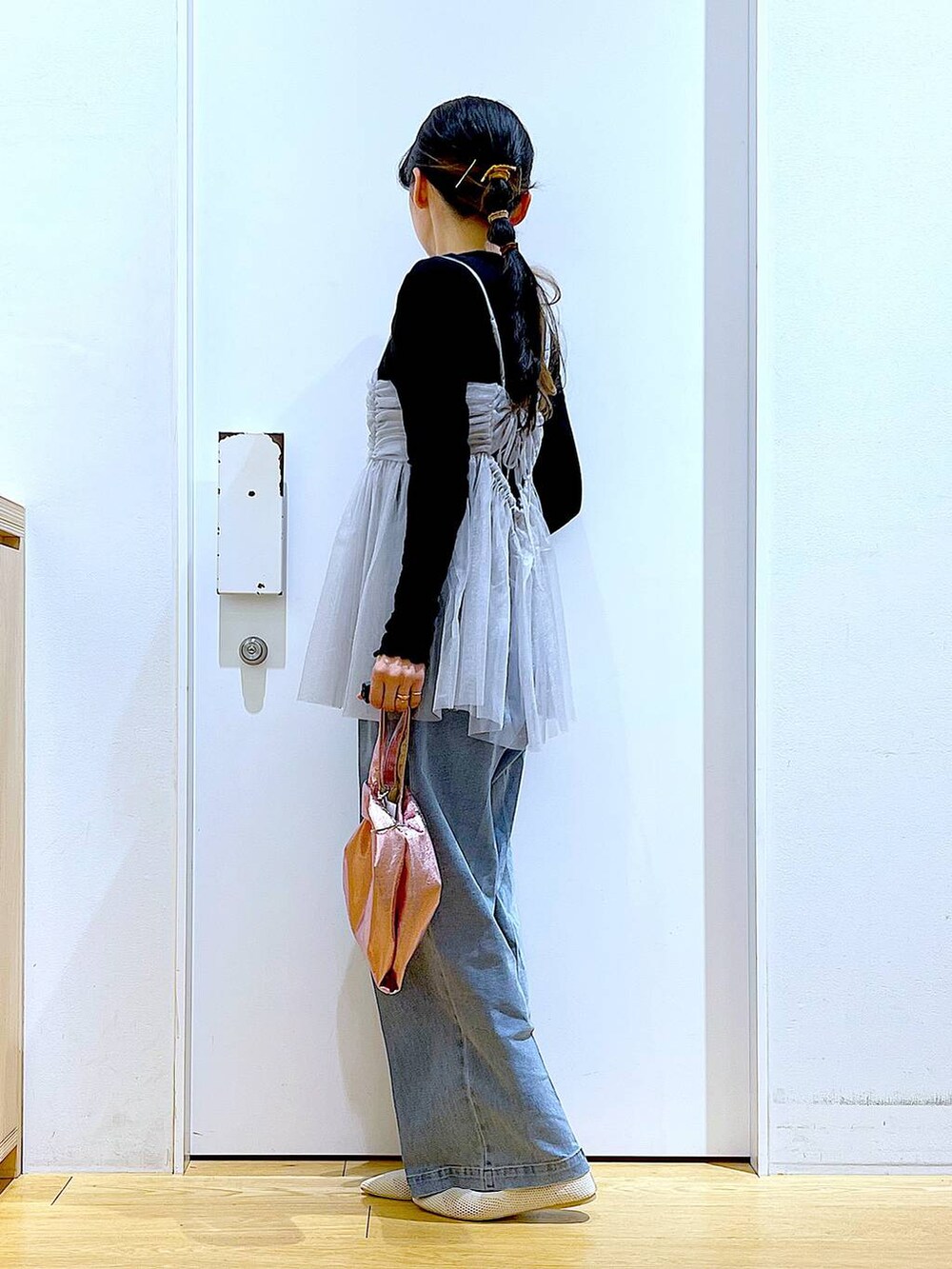 ブルー系のデニムパンツ、ピンク系のショルダーバッグ、ホワイト系のパンプスを着用したレディースの春コーディネートの3枚目の写真