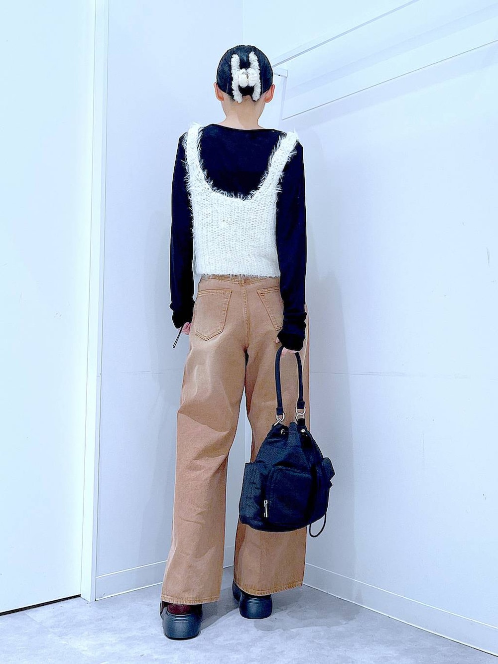 ブラウン系のデニムパンツ、ブラック系のハンドバッグ、ブラック系のTシャツ/カットソーを着用したレディースの秋コーディネートの5枚目の写真
