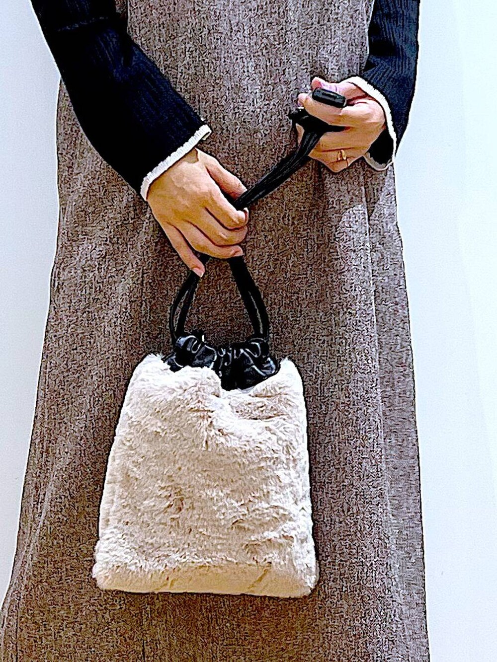 ブラック系のニット/セーター、ブラウン系のブーツ、ベージュ系のショルダーバッグを着用したレディースの冬コーディネートの9枚目の写真