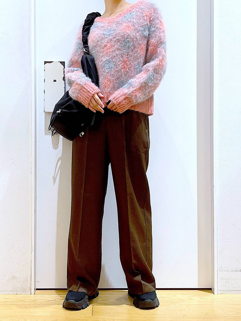 ブラック系のブーツ、ブラック系のショルダーバッグ、ピンク系のニット/セーターを着用したレディースの冬コーディネートの6枚目の写真