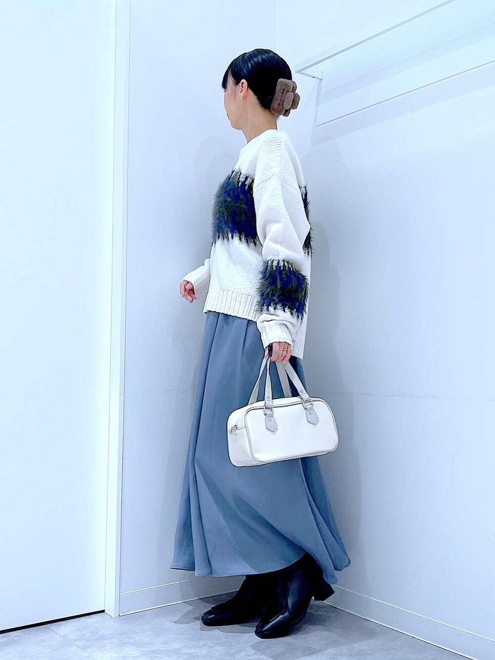 ブラック系のブーツ、ホワイト系のショルダーバッグ、ホワイト系のニット/セーターを着用したレディースの冬コーディネートの3枚目の写真