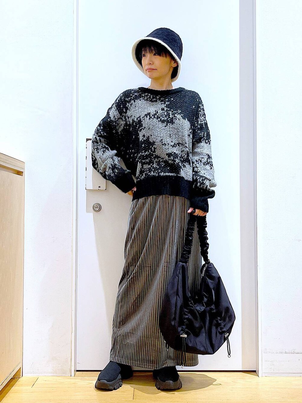 ブラック系のショルダーバッグ、グレー系のスカート、ブラック系のブーツを着用したレディースの冬コーディネートの2枚目の写真