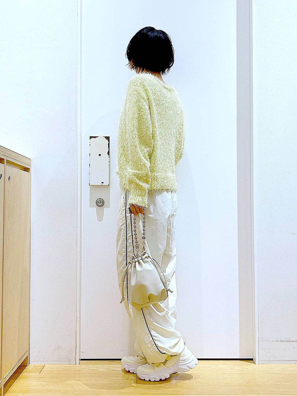 ベージュ系のショルダーバッグ、ホワイト系のスニーカー、イエロー系のカーディガン/ボレロを着用したレディースの秋コーディネートの3枚目の写真