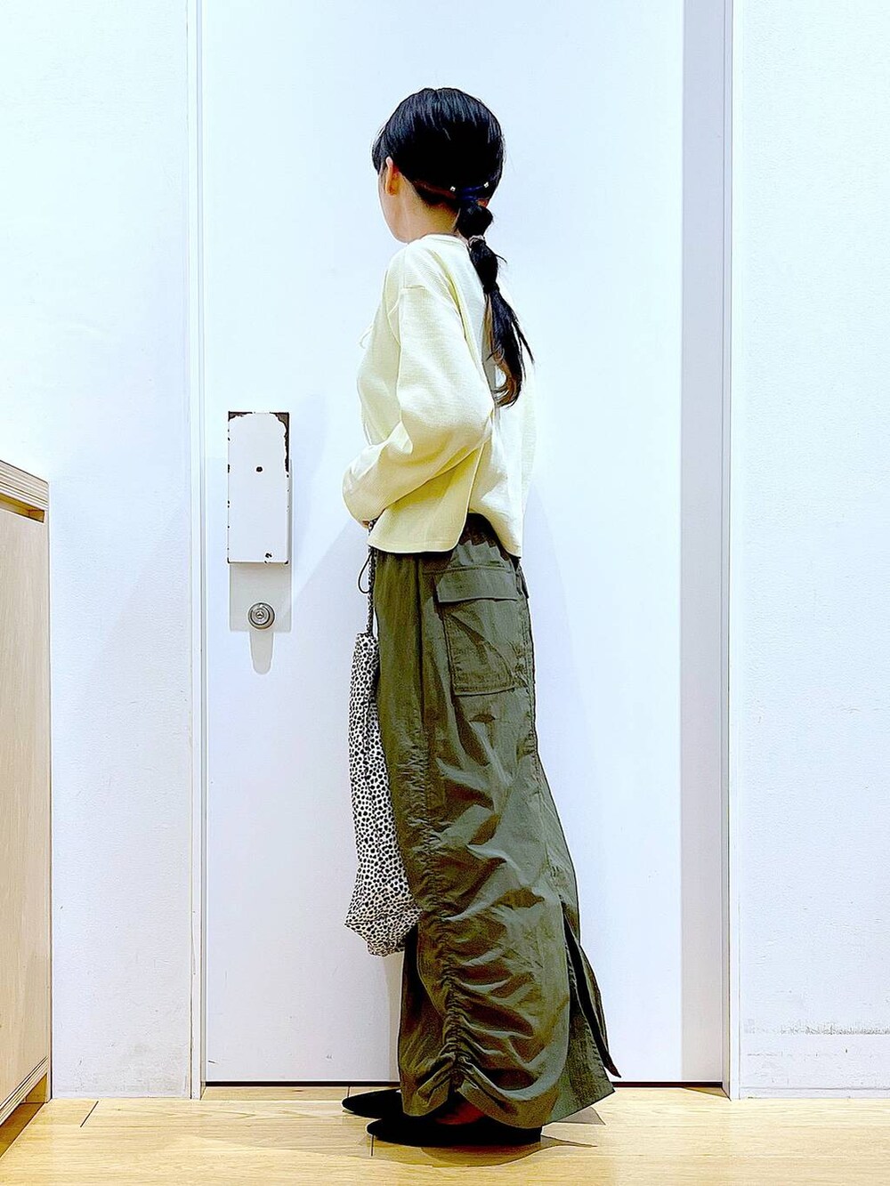 イエロー系のカーディガン/ボレロ、グリーン系のスカート、ベージュ系のトートバッグを着用したレディースの春コーディネートの3枚目の写真