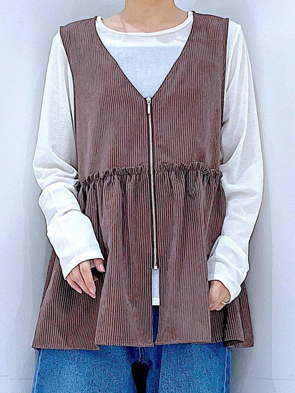 ブルー系のデニムパンツ、ブラウン系のベスト、ホワイト系のTシャツ/カットソーを着用したレディースの秋コーディネートの7枚目の写真