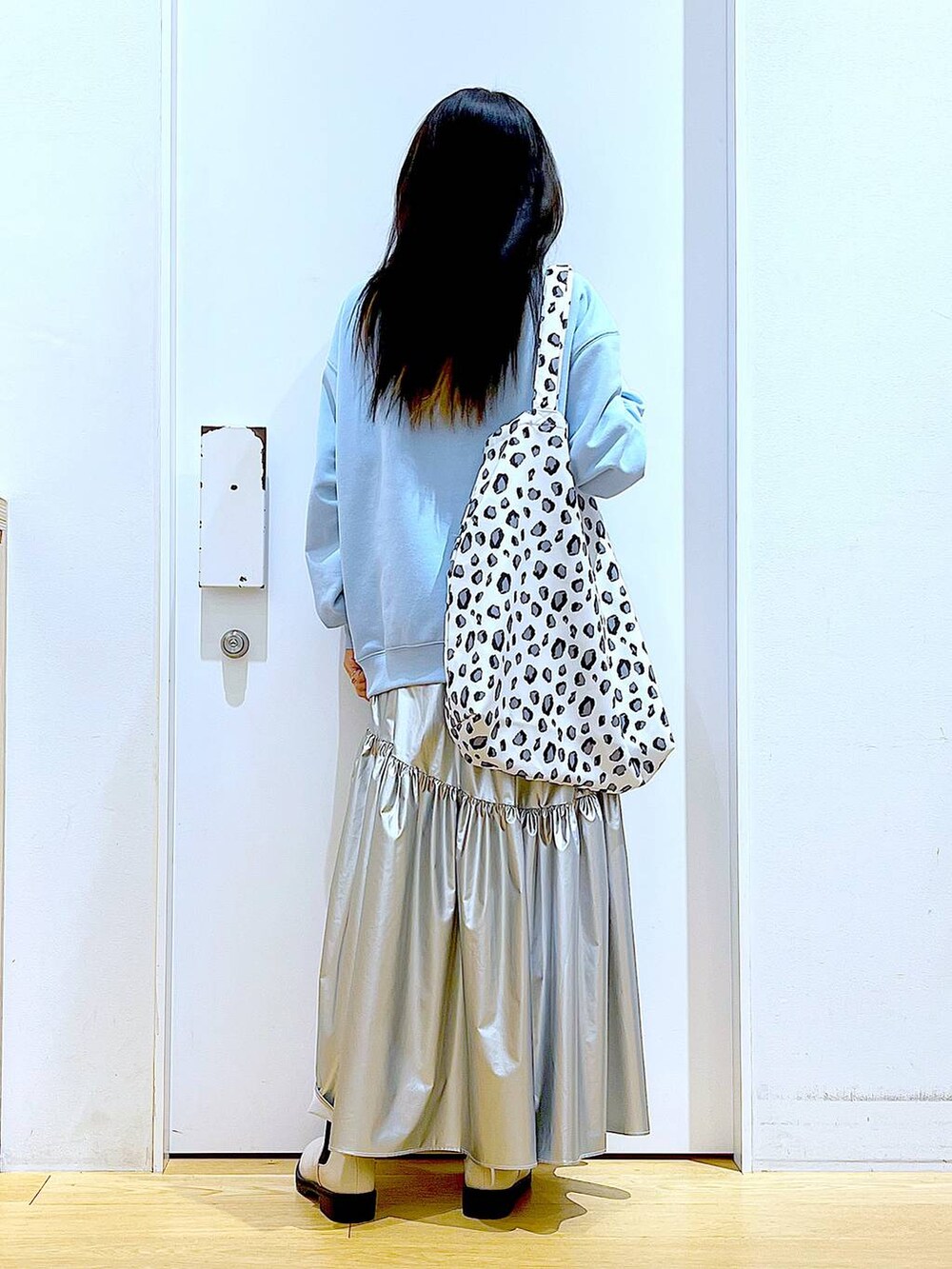 ブルー系のスウェット、シルバー系のスカート、ベージュ系のブーツを着用したレディースの春コーディネートの5枚目の写真