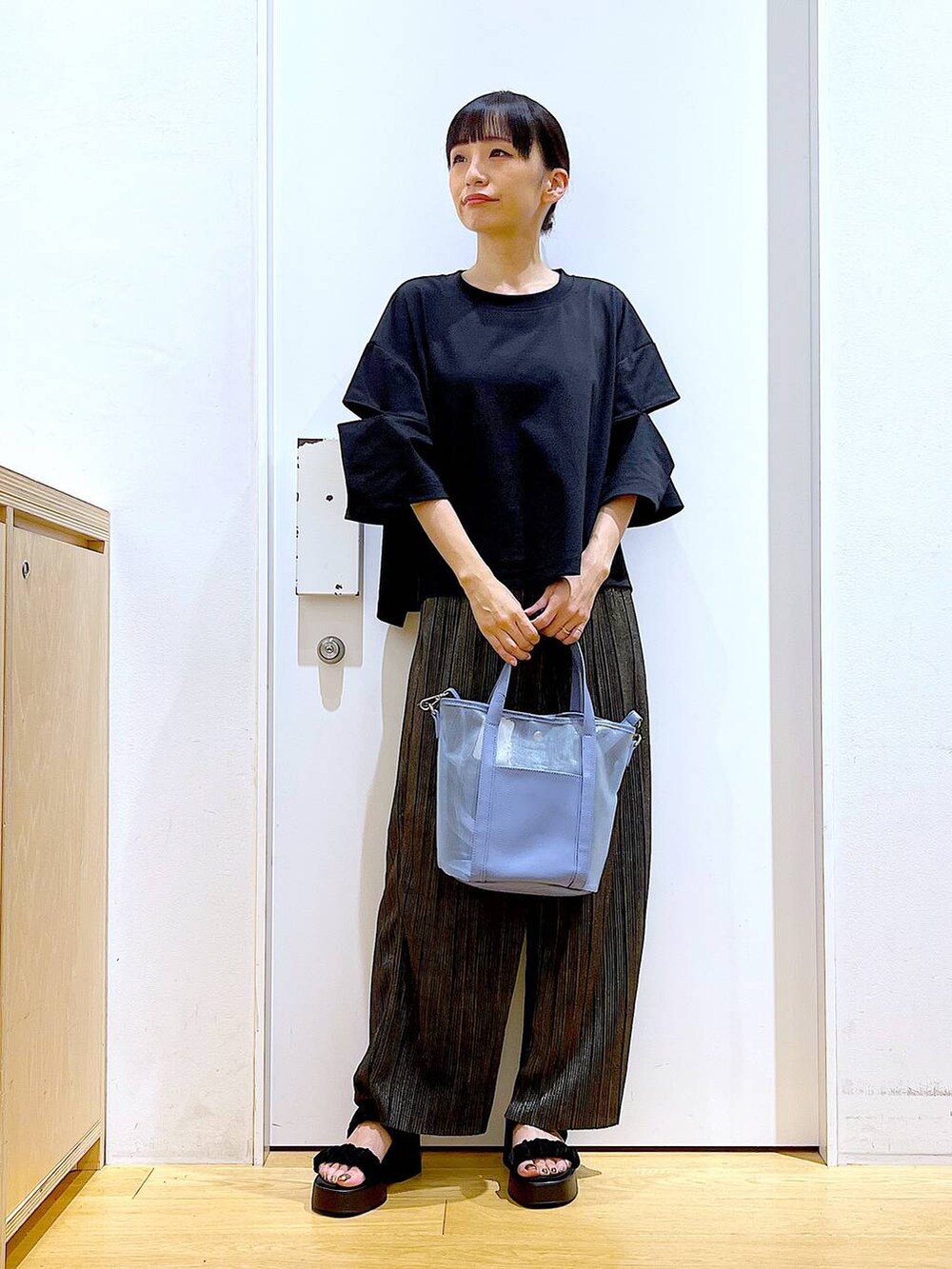 ブラック系のサンダル、ブルー系のトートバッグ、ブラック系のTシャツ/カットソーを着用したレディースの秋コーディネートの2枚目の写真