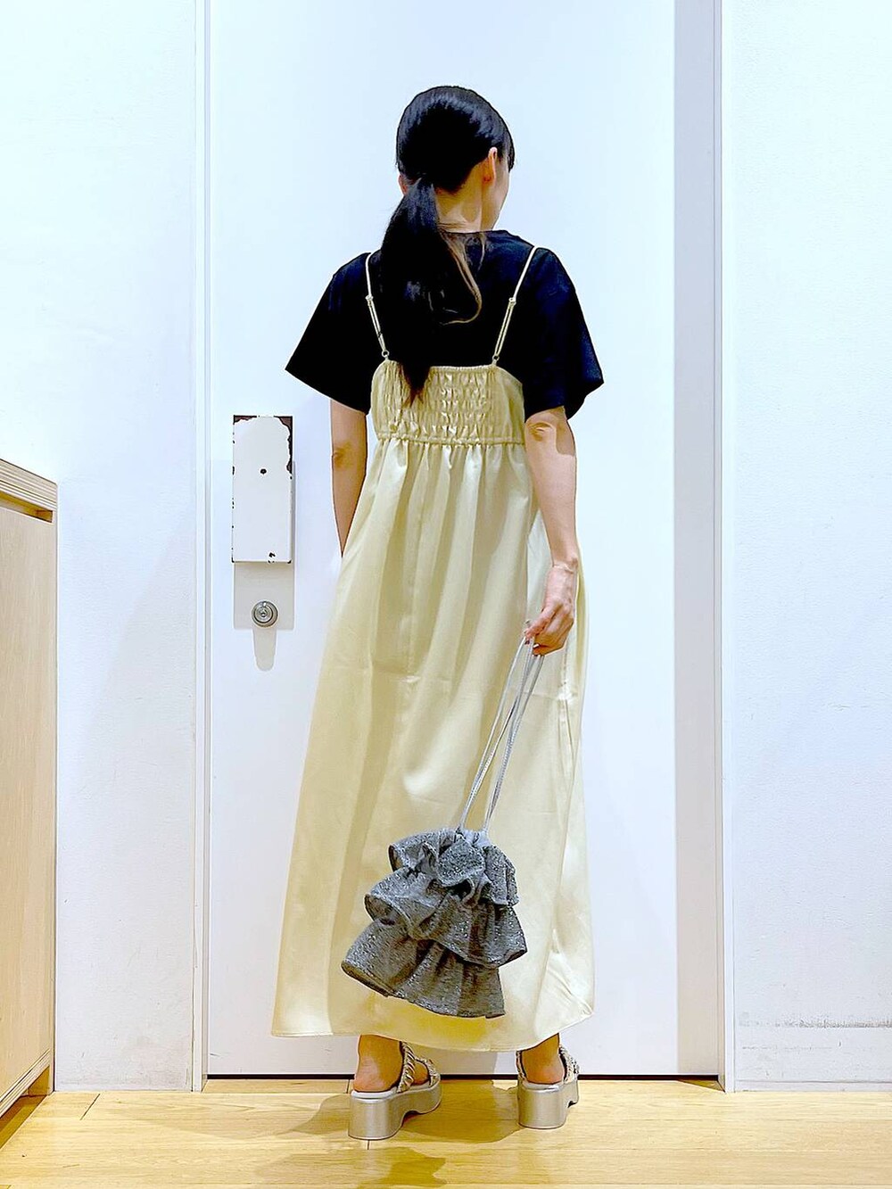 シルバー系のショルダーバッグ、シルバー系のサンダル、ブラック系のTシャツ/カットソーを着用したレディースの夏コーディネートの6枚目の写真