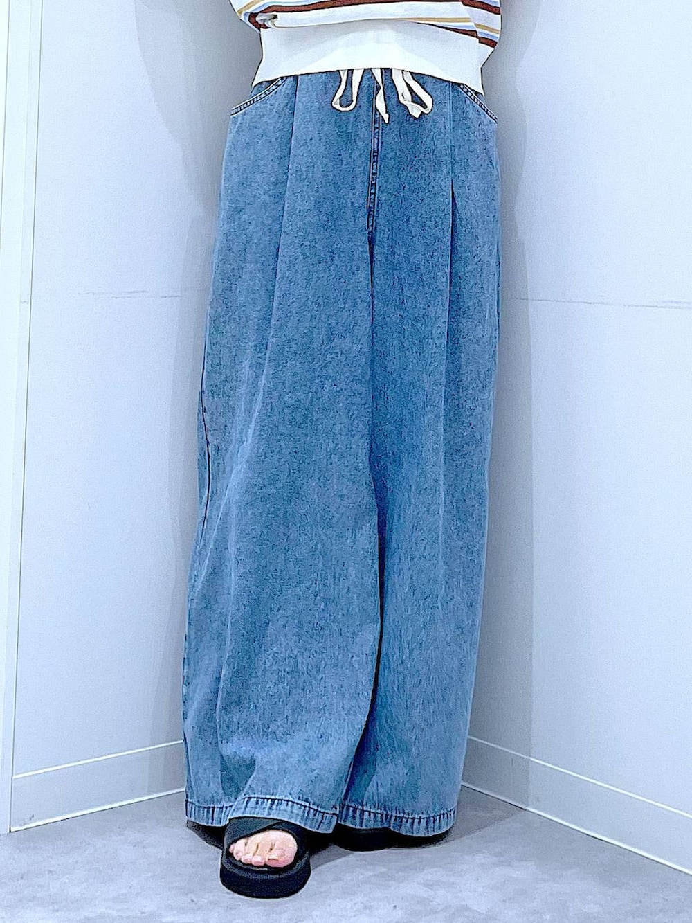 ブラック系のサンダル、ブルー系のデニムパンツ、ホワイト系のトートバッグを着用したレディースの夏コーディネートの8枚目の写真