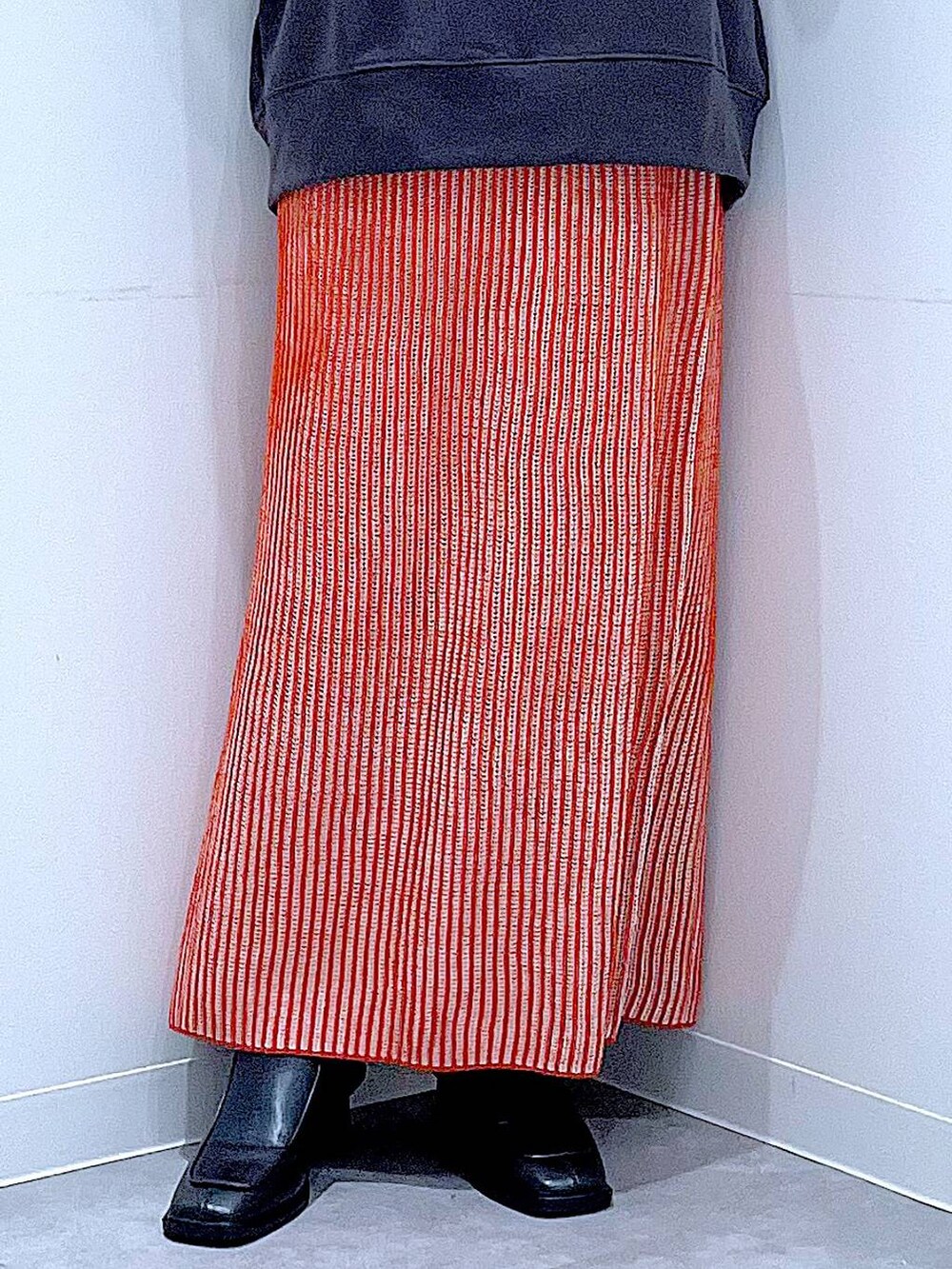 オレンジ系のスカート、ブラック系のブーツ、ブラック系のショルダーバッグを着用したレディースの秋コーディネートの8枚目の写真