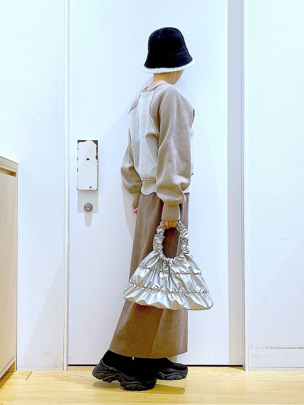 ブラック系のブーツ、ブラウン系のスカート、シルバー系のショルダーバッグを着用したレディースの冬コーディネートの4枚目の写真