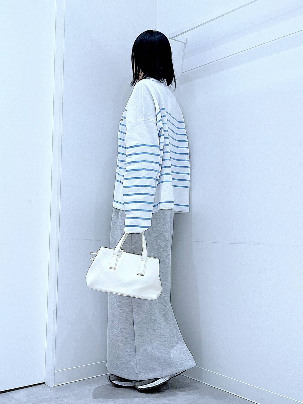 ホワイト系のボストンバッグ、グレー系のスカートを着用したレディースの春コーディネートの3枚目の写真