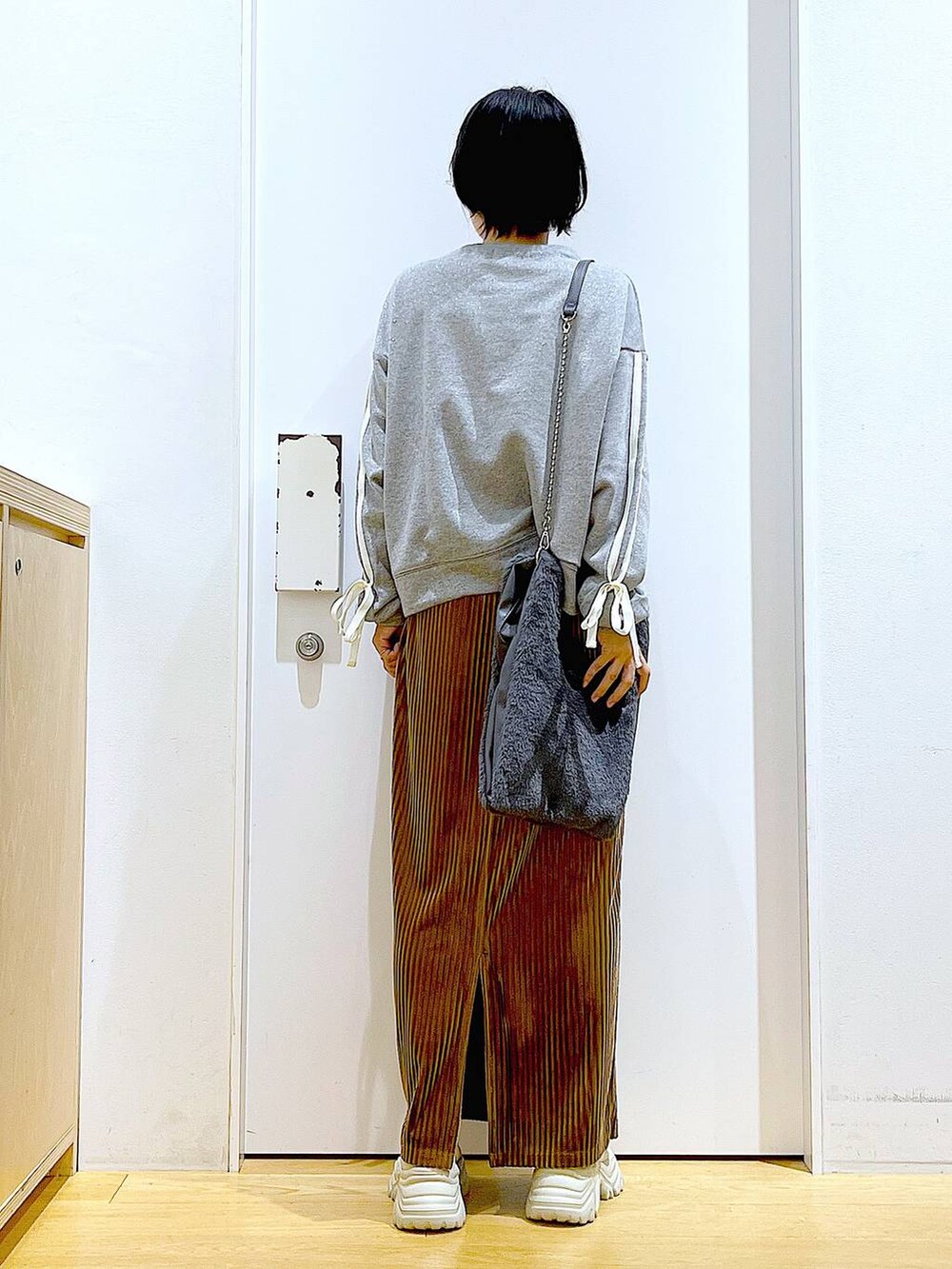 グレー系のショルダーバッグ、ブラウン系のスカート、ベージュ系のブーツを着用したレディースの秋コーディネートの5枚目の写真