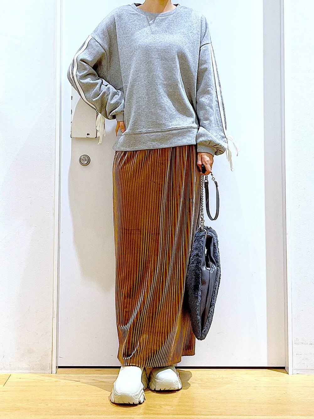 グレー系のショルダーバッグ、ブラウン系のスカート、ベージュ系のブーツを着用したレディースの秋コーディネートの6枚目の写真