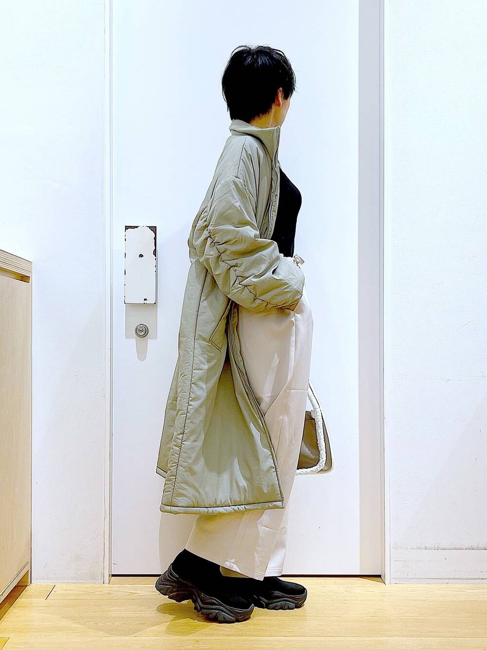 ブラック系のニット/セーター、ベージュ系のショルダーバッグ、ブラック系のブーツを着用したレディースの冬コーディネートの4枚目の写真