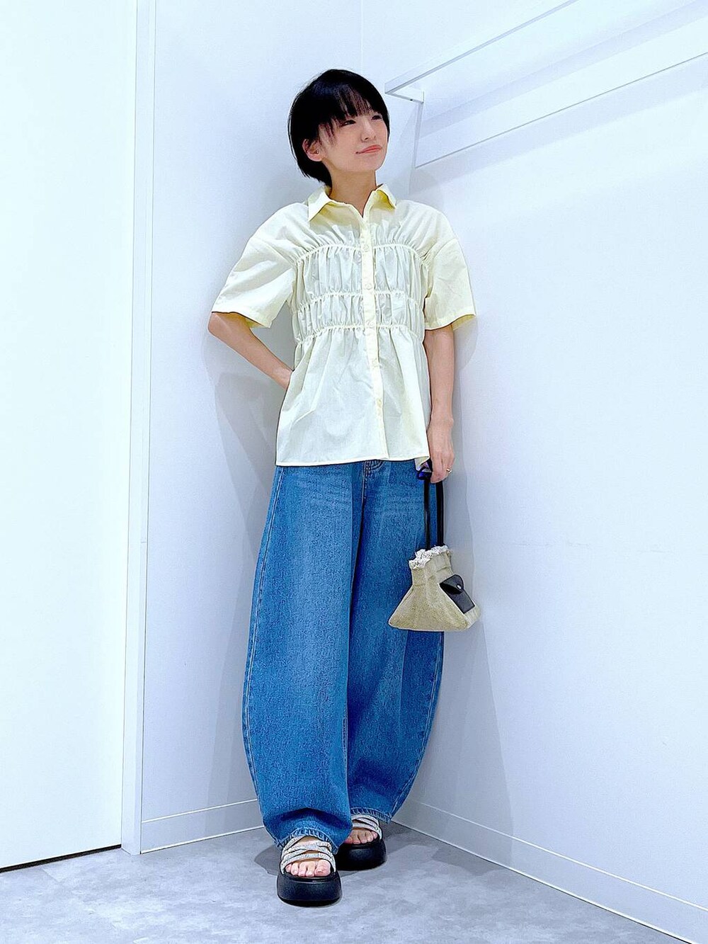 ブルー系のデニムパンツ、ベージュ系のショルダーバッグ、シルバー系のサンダルを着用したレディースの夏コーディネートの2枚目の写真