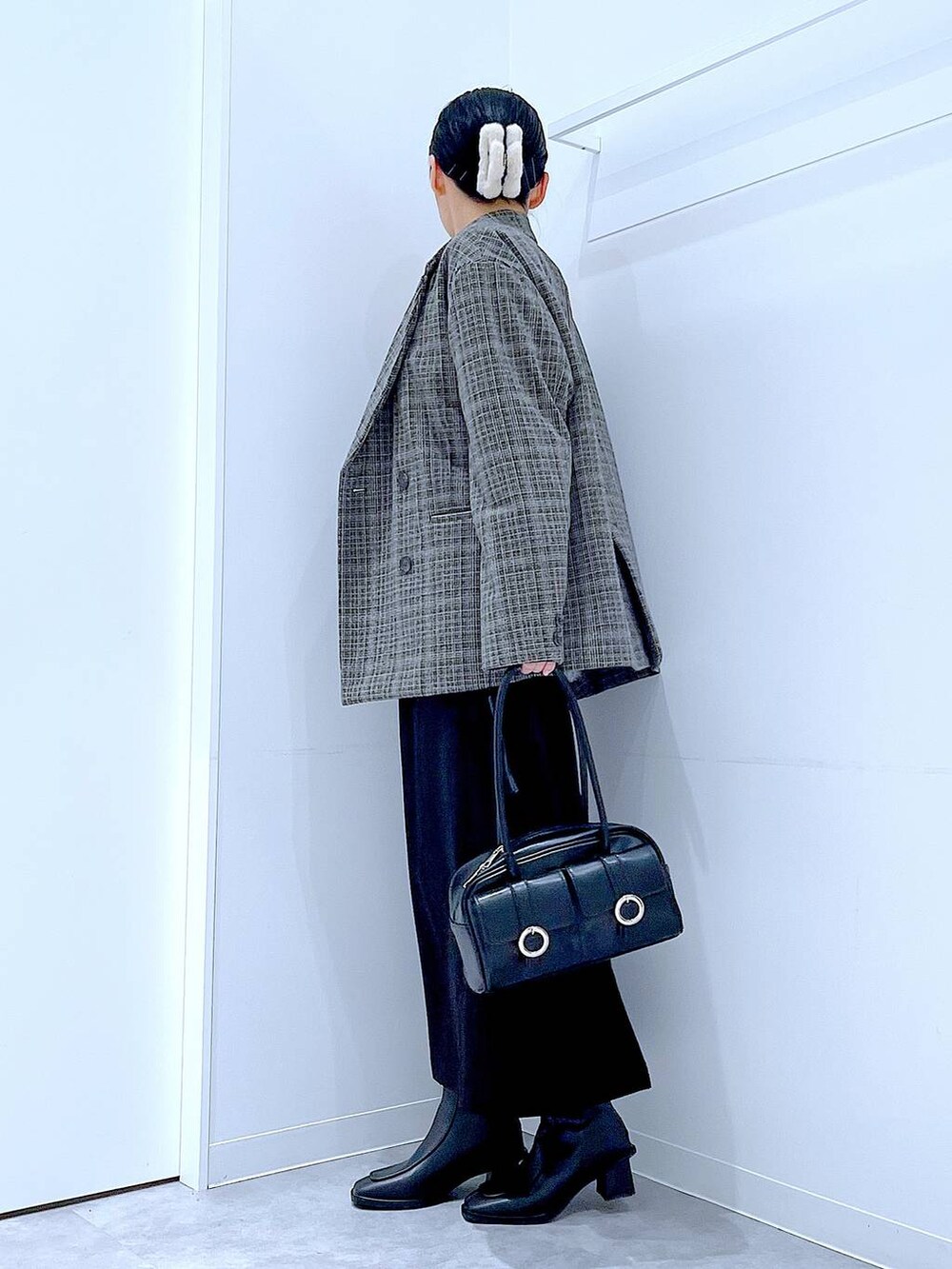 ブラック系のショルダーバッグ、ブラック系のスカート、ブラック系のブーツを着用したレディースの冬コーディネートの3枚目の写真