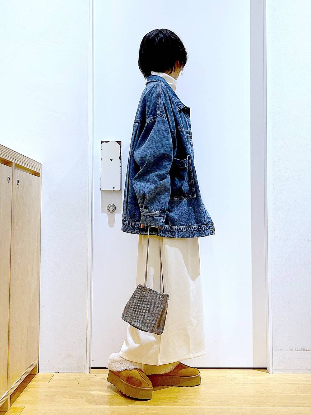 グレー系のショルダーバッグ、ベージュ系のワンピース、ベージュ系のスリッポンを着用したレディースの秋コーディネートの4枚目の写真