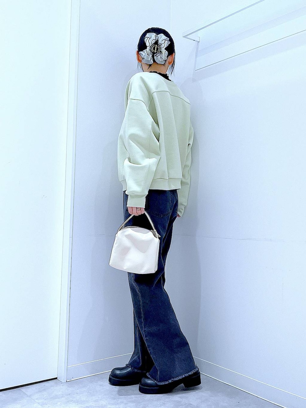 ホワイト系のショルダーバッグ、グリーン系のスウェット、ブラック系のデニムパンツを着用したレディースの春コーディネートの3枚目の写真