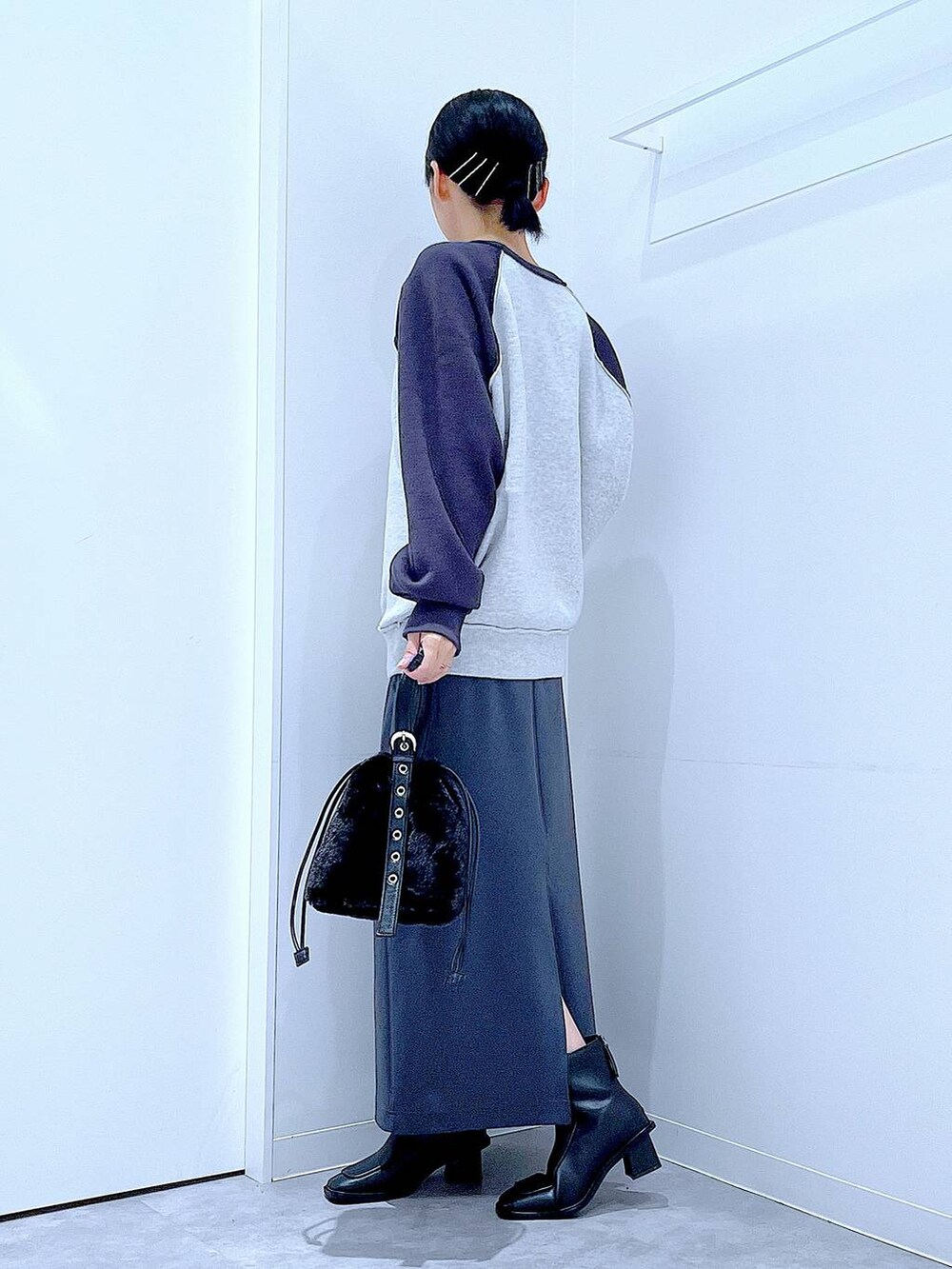 グレー系のスカート、グレー系のニット/セーター、ブラック系のブーツを着用したレディースの秋コーディネートの3枚目の写真