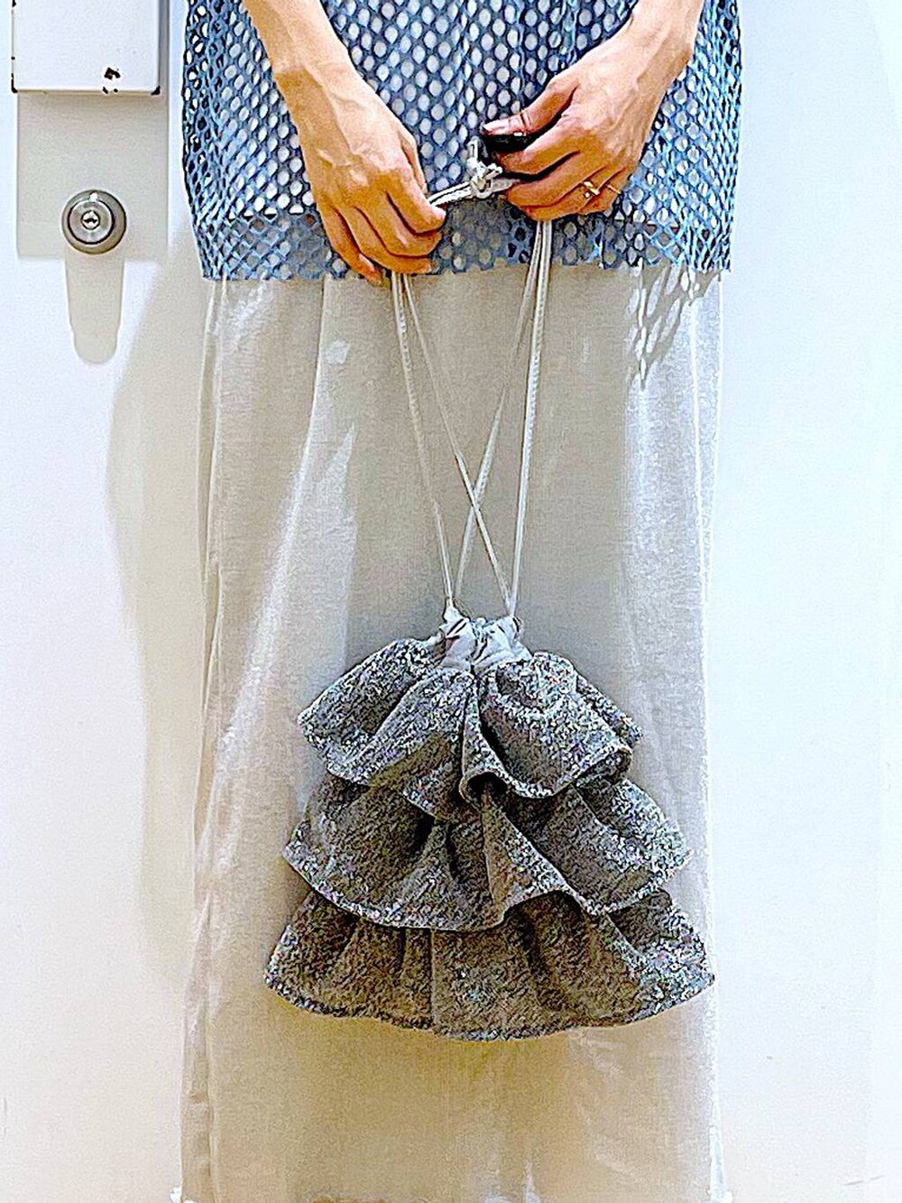 グレー系のスカート、シルバー系のショルダーバッグ、ホワイト系のTシャツ/カットソーを着用したレディースの夏コーディネートの9枚目の写真