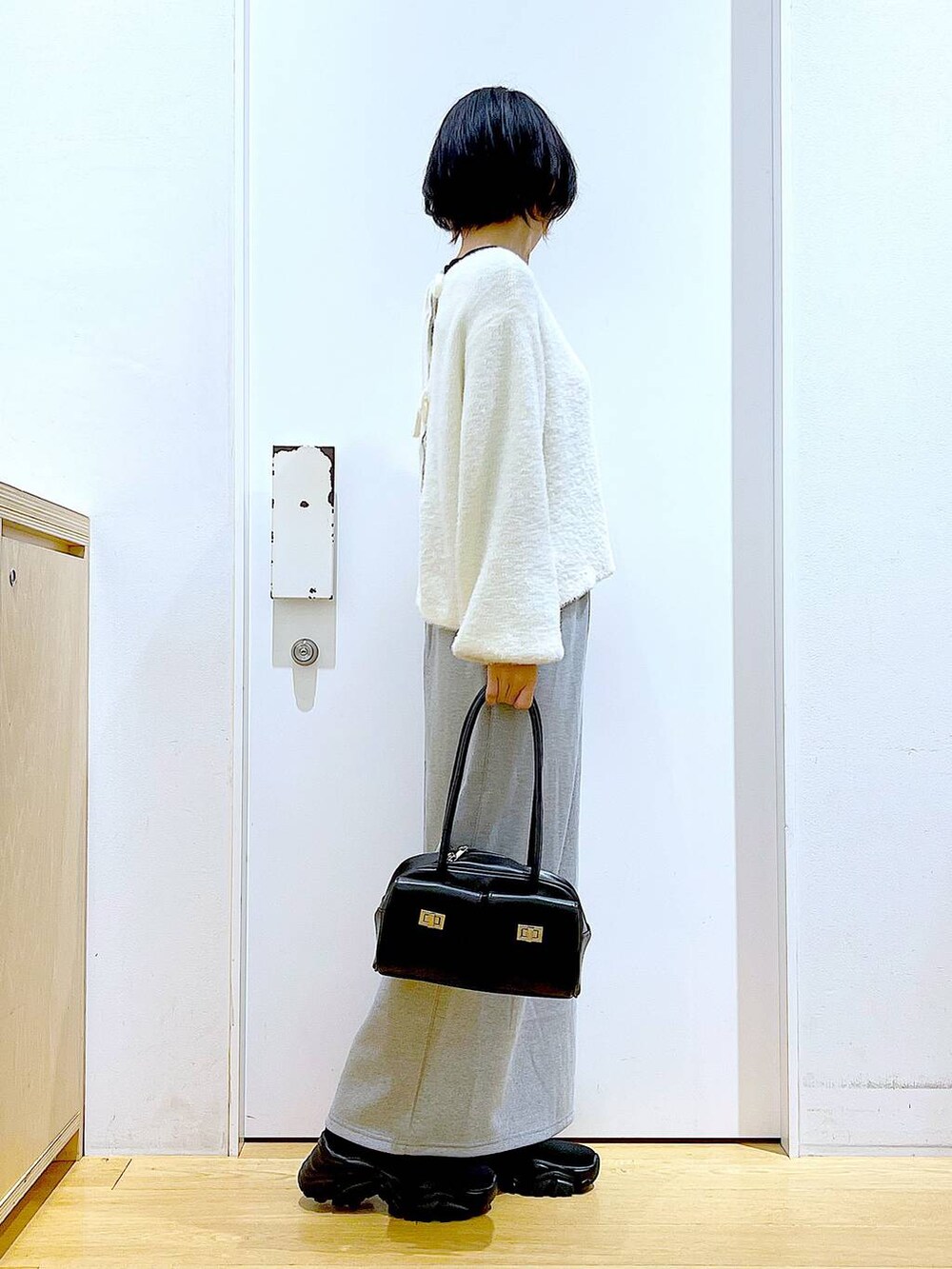 ブラック系のハンドバッグ、ブラック系のブーツ、グレー系のスカートを着用したレディースの冬コーディネートの4枚目の写真