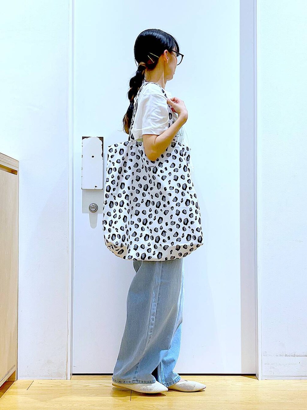 ブルー系のデニムパンツ、イエロー系のキャミソール、ホワイト系のトートバッグを着用したレディースの春コーディネートの4枚目の写真