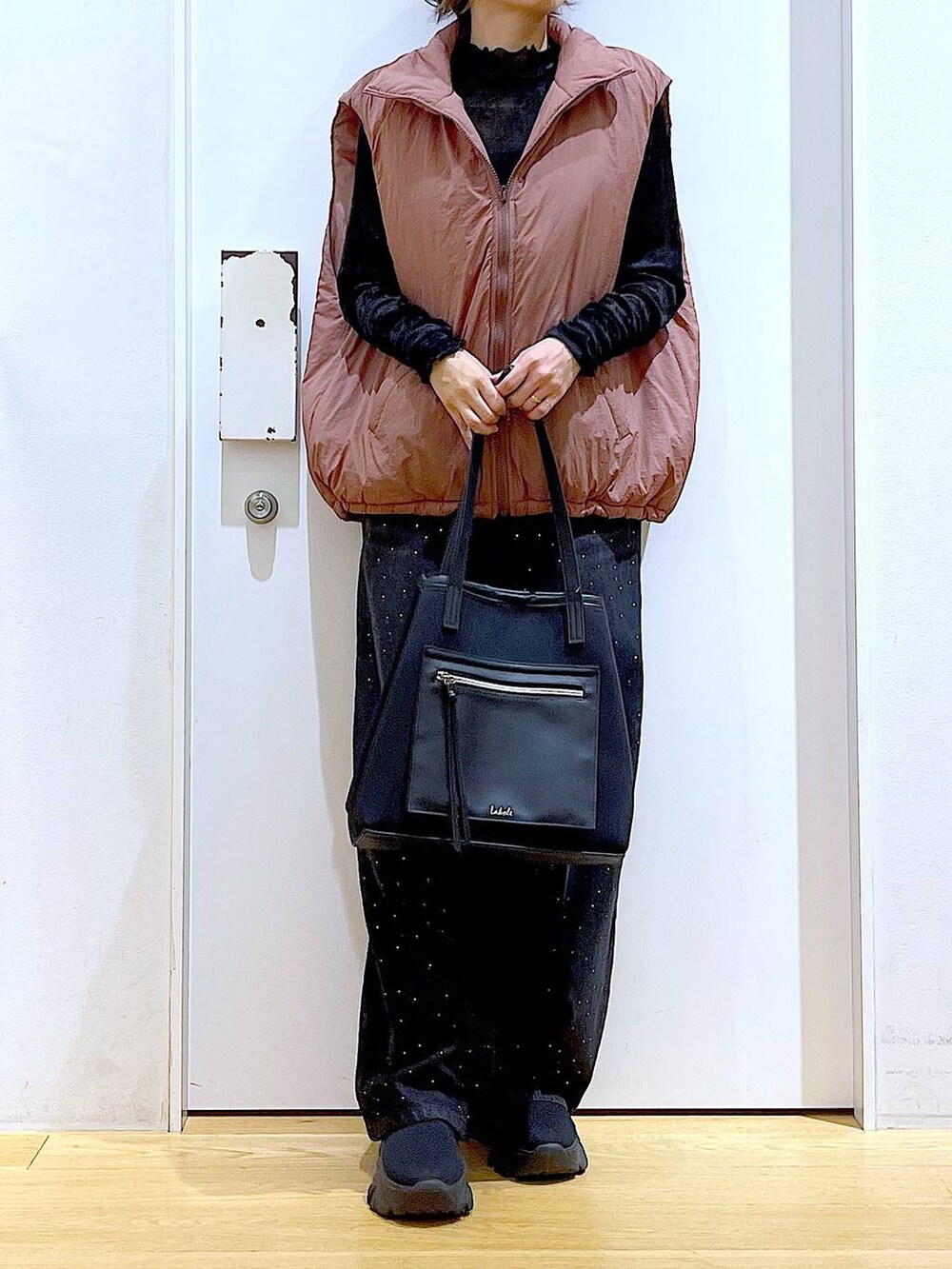 ブラウン系のベスト、ブラック系のトートバッグ、ブラック系のTシャツ/カットソーを着用したレディースの秋コーディネートの6枚目の写真