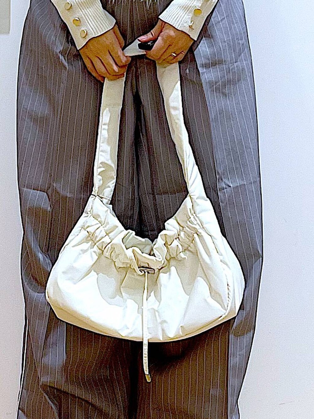 ホワイト系のニット/セーター、ホワイト系のハンドバッグ、グレー系のスラックスを着用したレディースの秋コーディネートの9枚目の写真