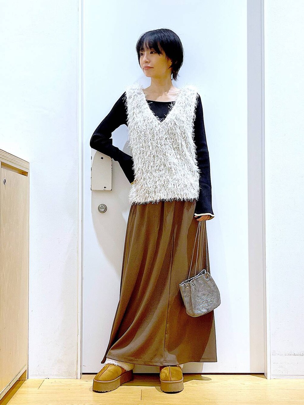 ブラック系のニット/セーター、グレー系のショルダーバッグ、ベージュ系のベストを着用したレディースの秋コーディネートの2枚目の写真