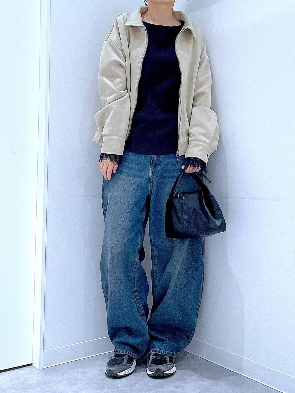 ブルー系のデニムパンツ、ブラック系のショルダーバッグ、ベージュ系のブルゾンを着用したレディースの春コーディネートの6枚目の写真