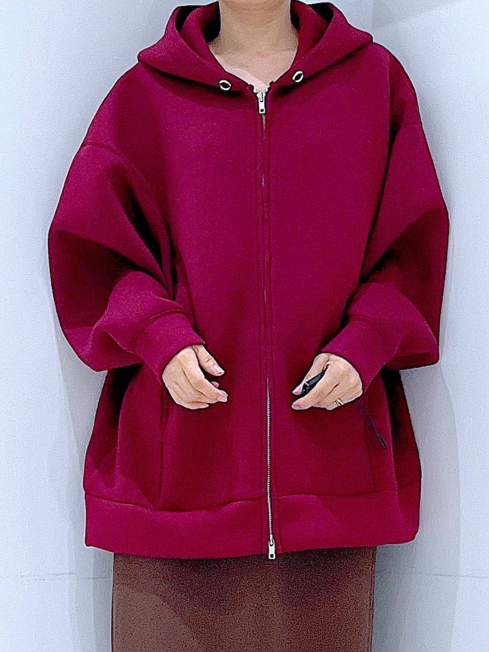 レッド系のパーカー、ブラウン系のスカート、グレー系のトートバッグを着用したレディースの秋コーディネートの7枚目の写真