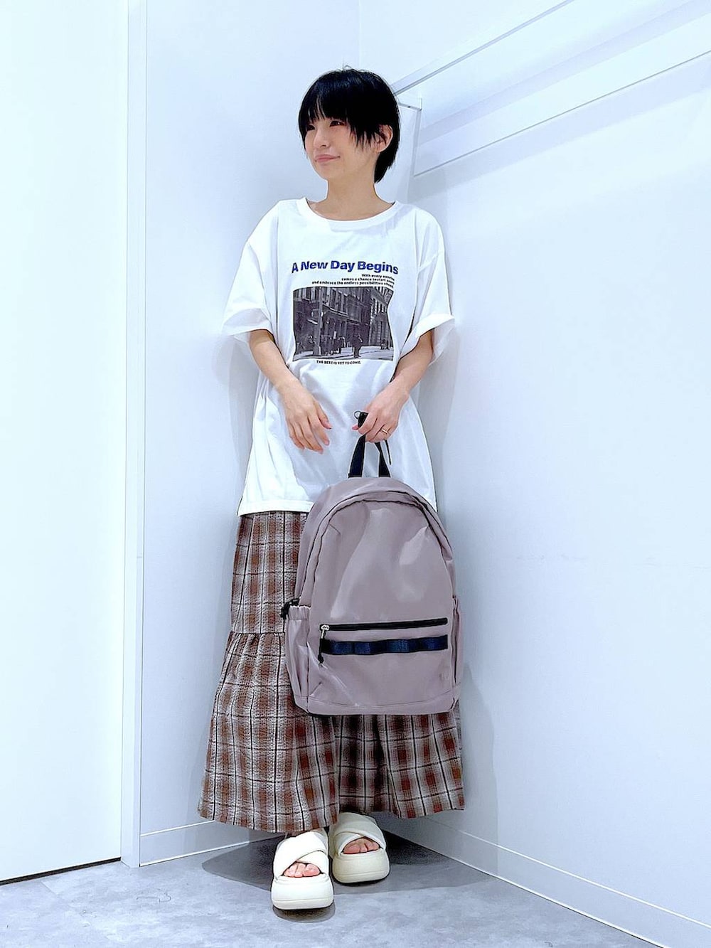 ベージュ系のバックパック/リュック、ホワイト系のサンダル、ブラウン系のワンピースを着用したレディースの夏コーディネートの2枚目の写真