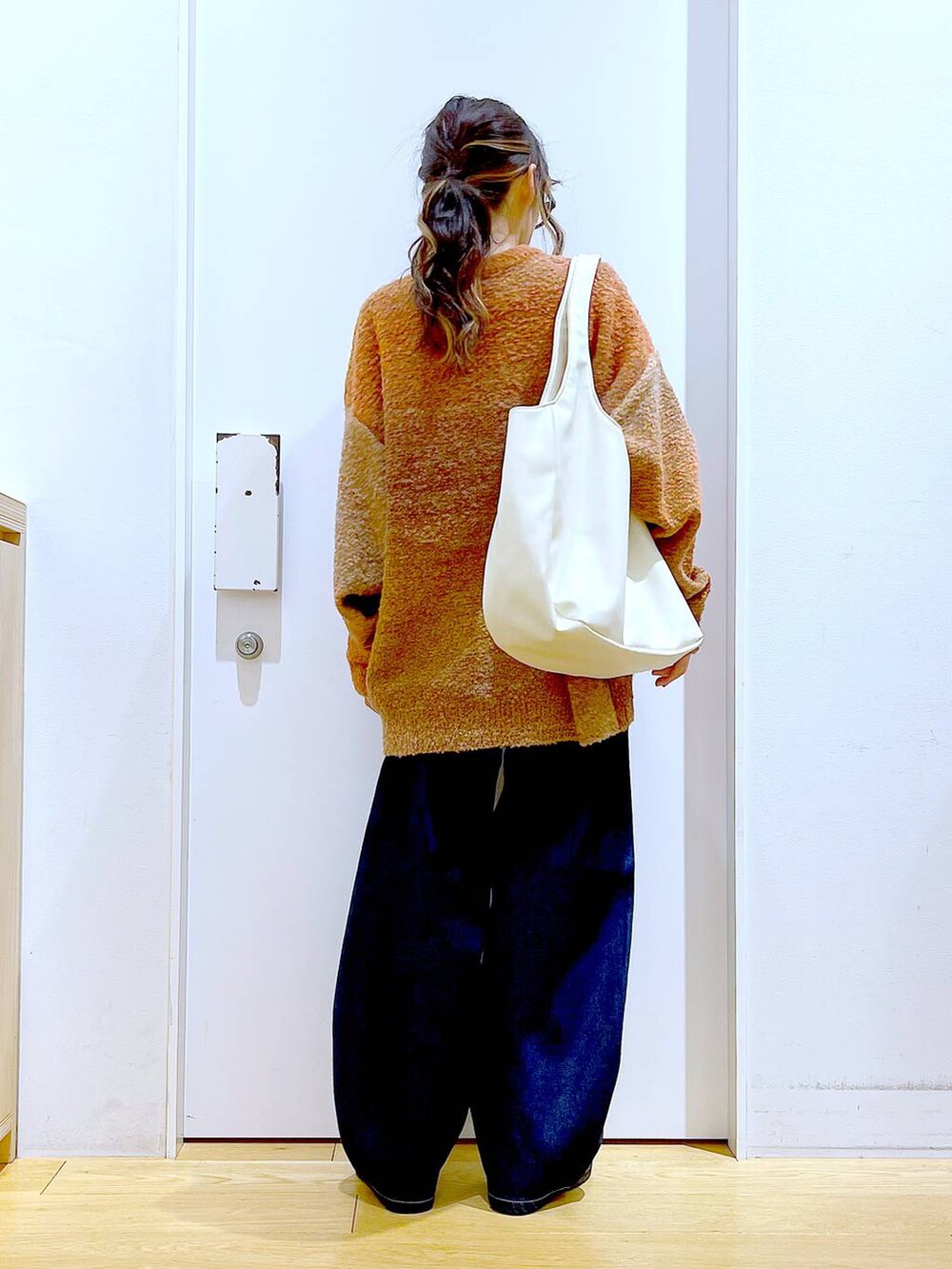 オレンジ系のニット/セーター、ホワイト系のトートバッグ、ベージュ系のブーツを着用したレディースの冬コーディネートの5枚目の写真