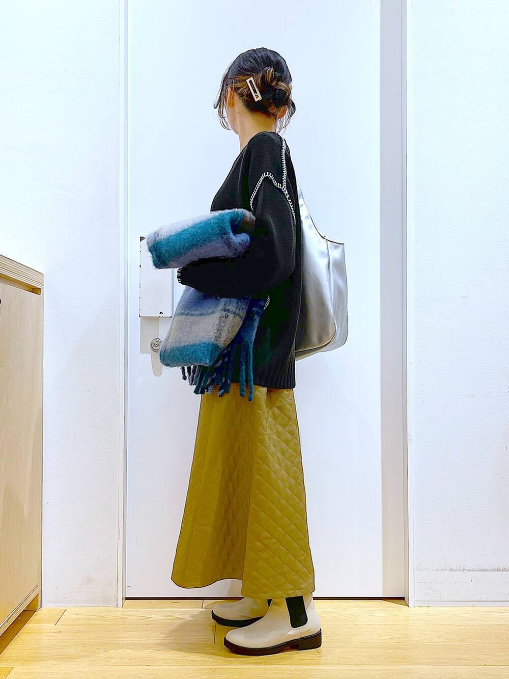 シルバー系のトートバッグ、ベージュ系のブーツ、ブラック系のニット/セーターを着用したレディースの冬コーディネートの3枚目の写真