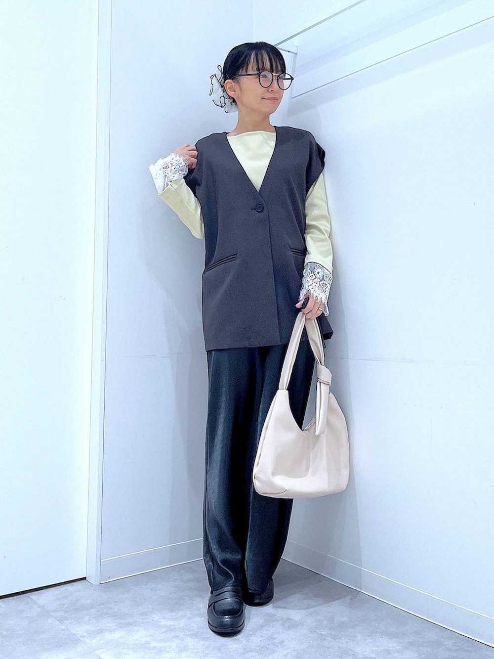 ブラック系のスカート、グレー系のベスト、ブラック系のローファーを着用したレディースの春コーディネートの2枚目の写真