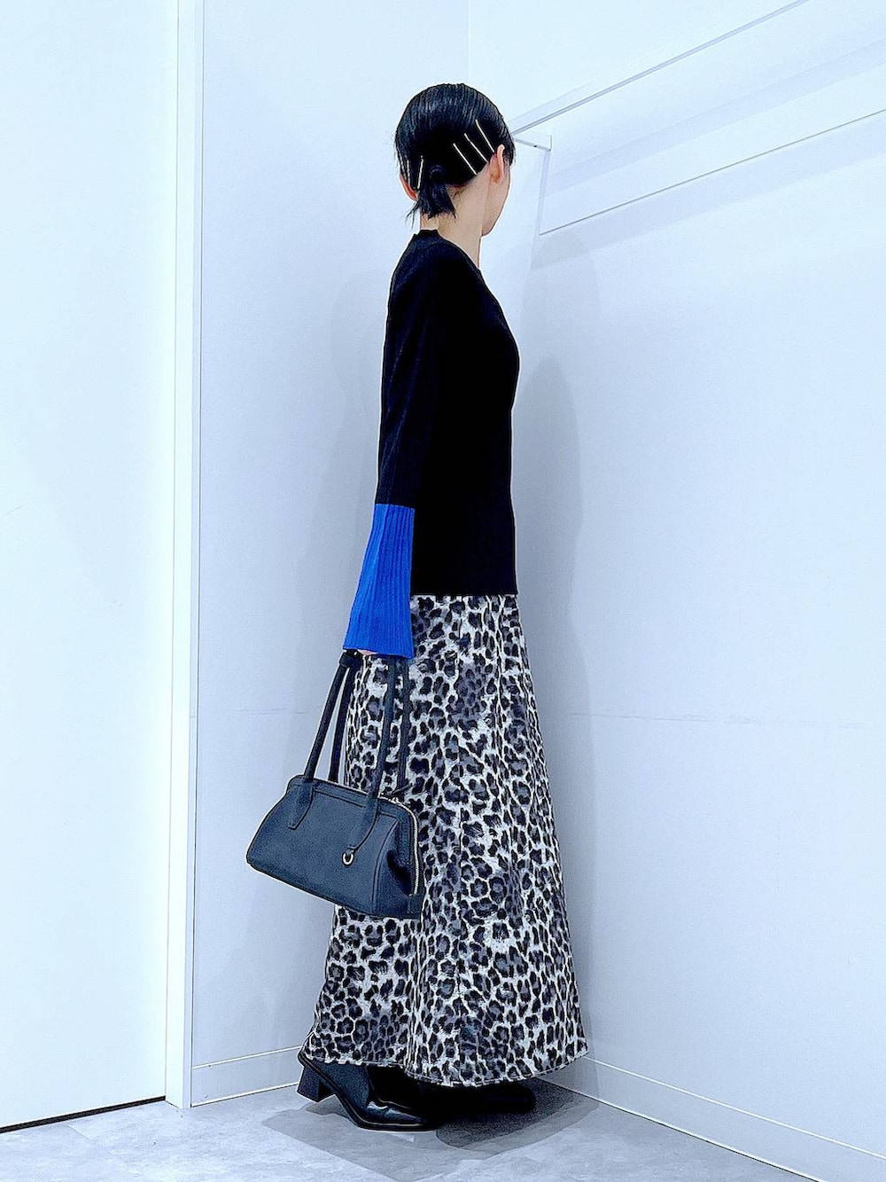 ブラック系のニット/セーター、ブラック系のブーツ、グレー系のスカートを着用したレディースの秋コーディネートの4枚目の写真