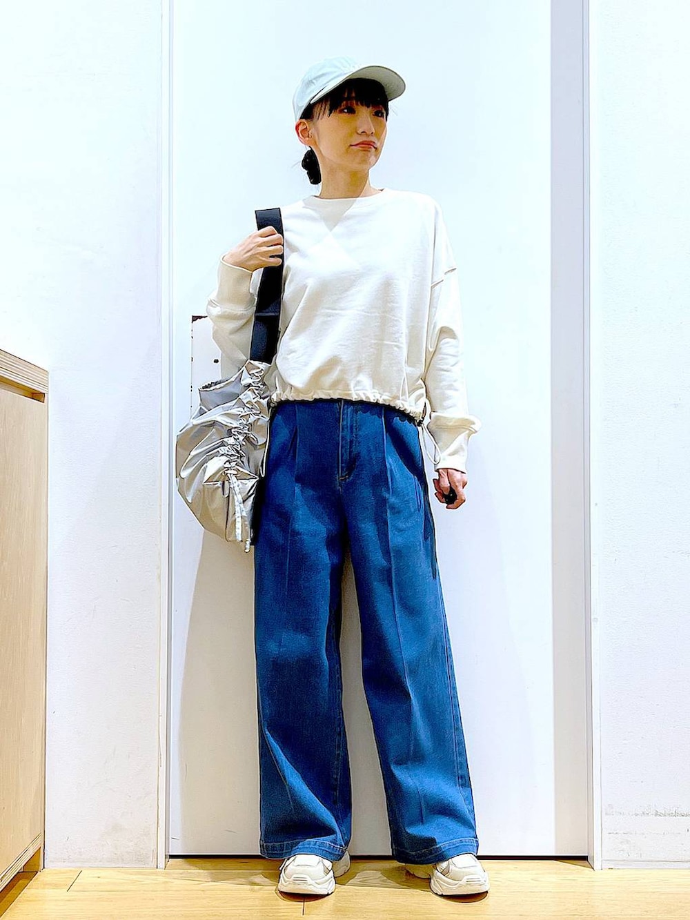 ホワイト系のスウェット、ブルー系のデニムパンツ、ベージュ系のスニーカーを着用したレディースの冬コーディネートの2枚目の写真