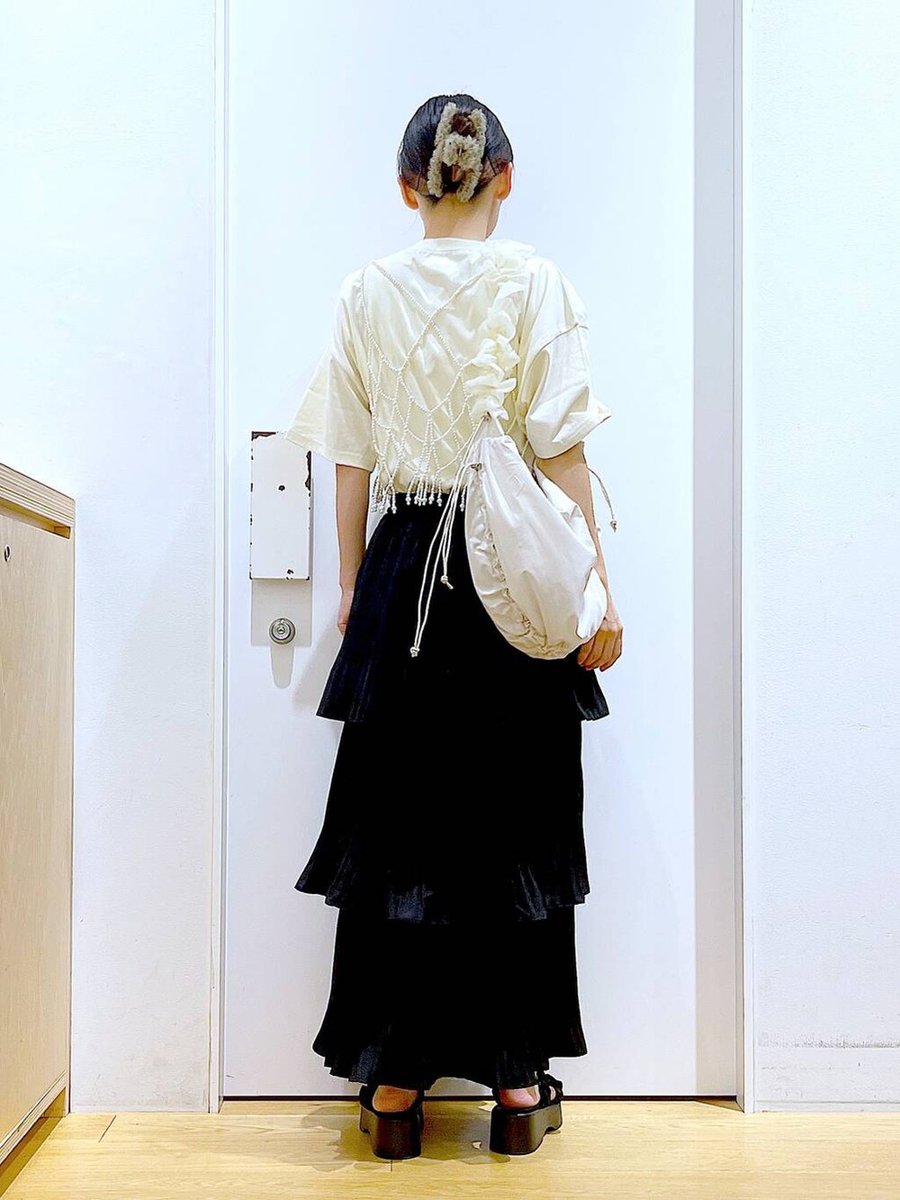 ブラック系のスカート、ブラック系のサンダル、ホワイト系のベストを着用したレディースの秋コーディネートの5枚目の写真