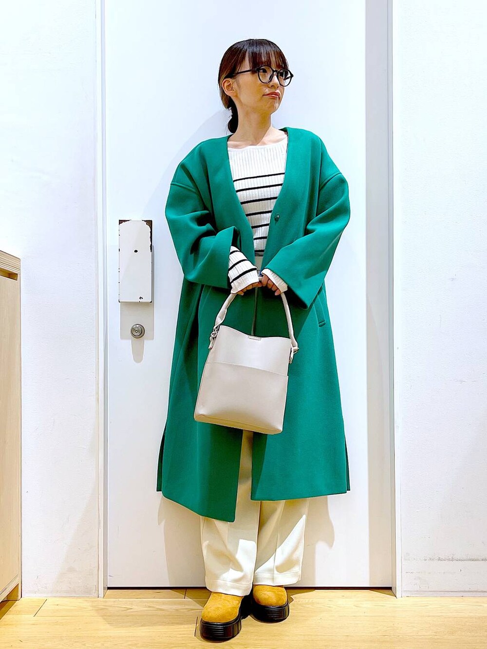 グレー系のショルダーバッグ、ホワイト系のニット/セーター、ベージュ系のブーツを着用したレディースの冬コーディネートの2枚目の写真