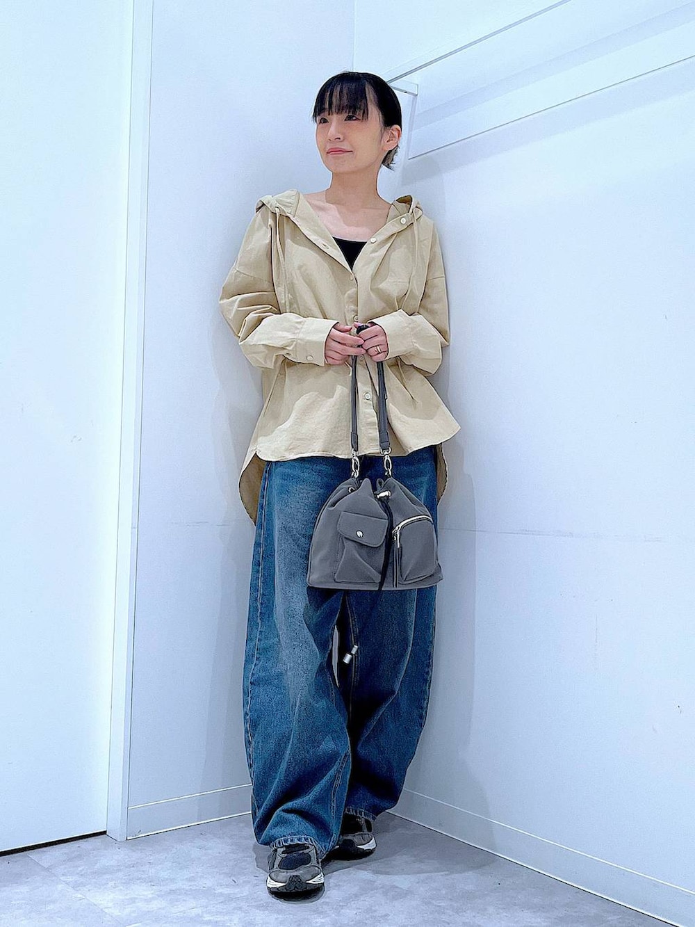 ブルー系のデニムパンツ、グレー系のショルダーバッグ、ベージュ系のその他トップスを着用したレディースの春コーディネートの2枚目の写真