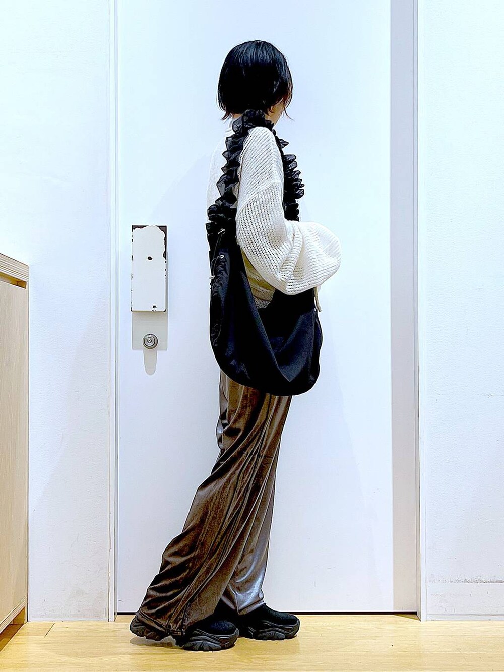 ブラック系のショルダーバッグ、ブラック系のブーツ、ホワイト系のニット/セーターを着用したレディースの冬コーディネートの4枚目の写真