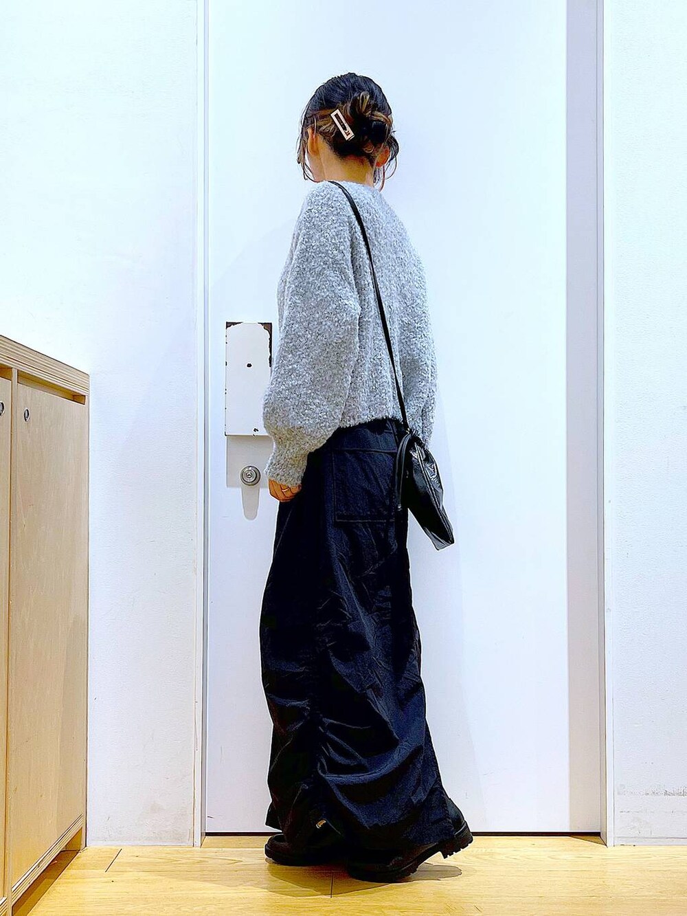 ブラック系のブーツ、ブラック系のスカート、ブラック系のショルダーバッグを着用したレディースの冬コーディネートの3枚目の写真