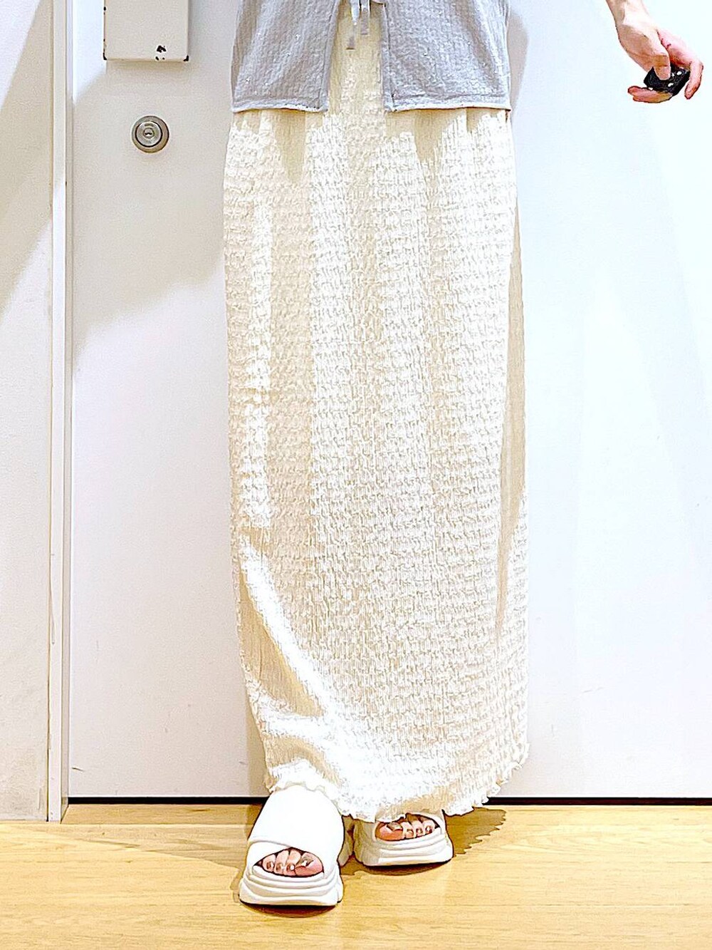 シルバー系のショルダーバッグ、ホワイト系のニット/セーター、ホワイト系のサンダルを着用したレディースの夏コーディネートの8枚目の写真