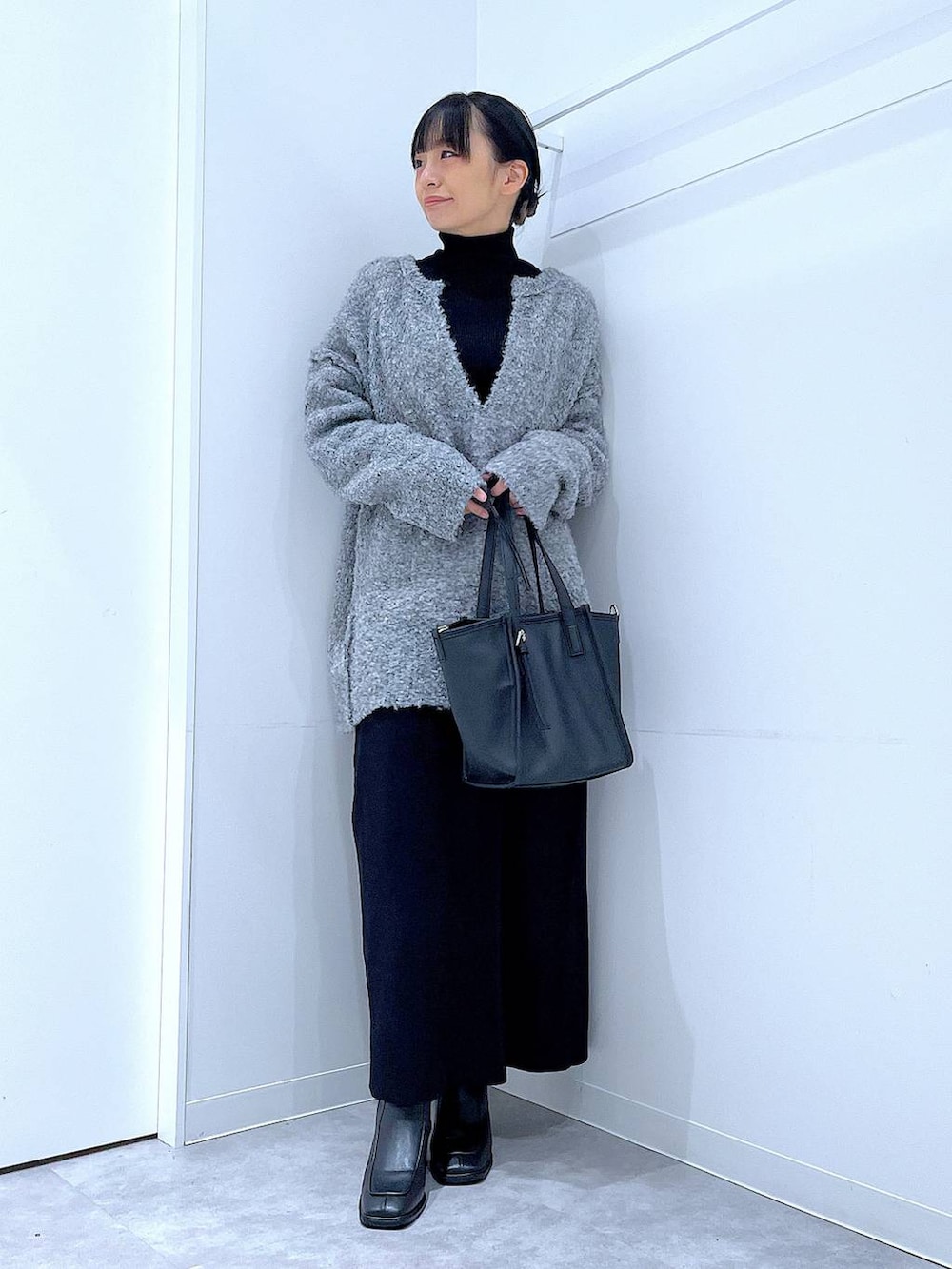 ブラック系のブーツ、グレー系のニット/セーター、ブラック系のスカートを着用したレディースの冬コーディネートの2枚目の写真