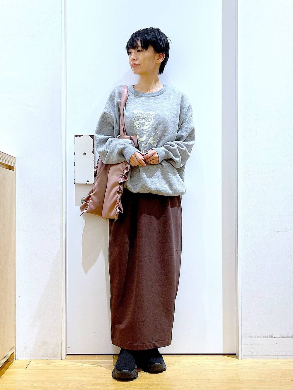 ブラック系のブーツ、ピンク系のトートバッグ、ブラウン系のスカートを着用したレディースの冬コーディネートの2枚目の写真