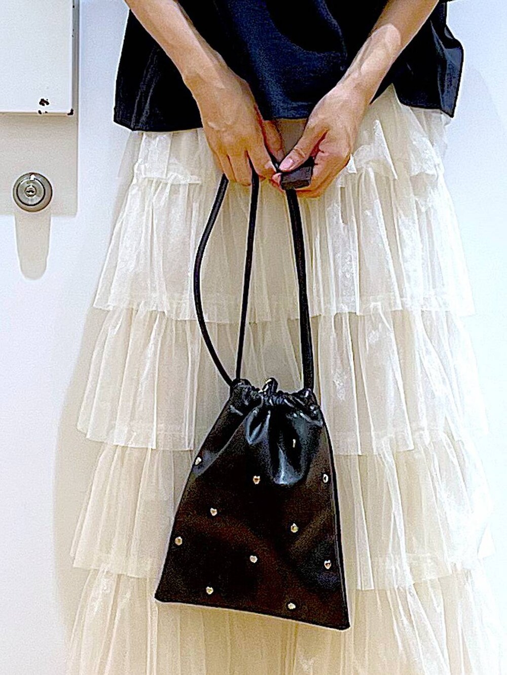 ブラック系のサンダル、ブラック系のショルダーバッグ、ベージュ系のスカートを着用したレディースの夏コーディネートの9枚目の写真