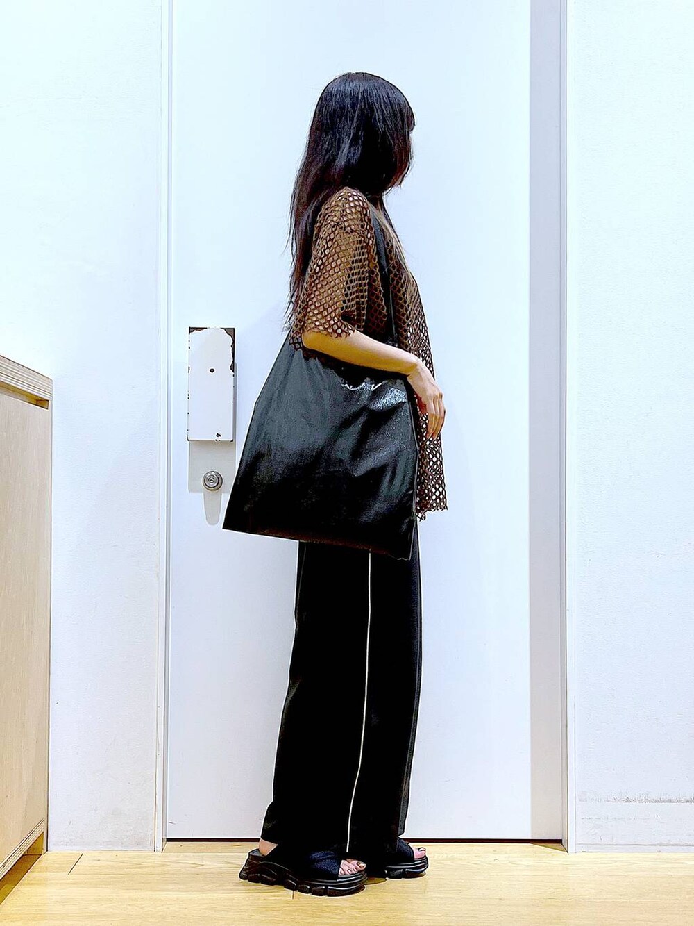 ブラック系のトートバッグ、ブラック系のニット/セーター、ブラック系のサンダルを着用したレディースの夏コーディネートの4枚目の写真